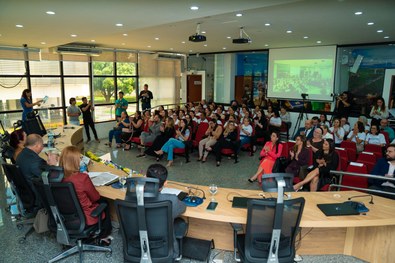 Plenário do TRE lotado de pessoas; e na bancada estão o presidente do TRE, um juiz, uma juíza e ...