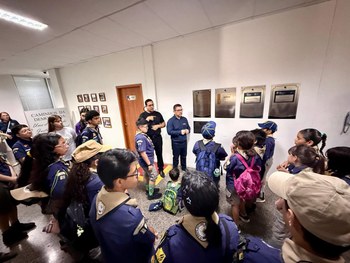 Um grande grupo de crianças, adolescentes e adultos escoteiros posa para uma foto em frente a um...
