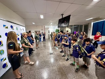 Um grande grupo de crianças, adolescentes e adultos escoteiros posa para uma foto em frente a um...