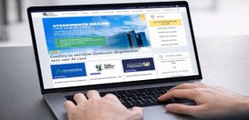 Foto de uma pessoa usando um notebook sobre uma mesa. As mãos estão no teclado. Na tela aparece ...