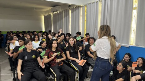 Em uma sala de aula, uma pessoa conduz uma atividade educativa diante de um grupo de estudantes ...