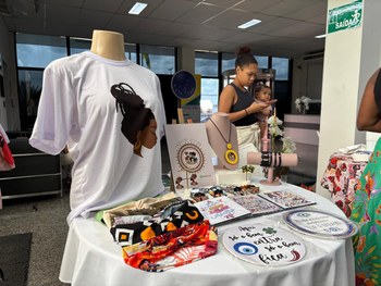 A imagem mostra uma mesa redonda coberta com toalha branca, onde estão expostos diversos itens a...