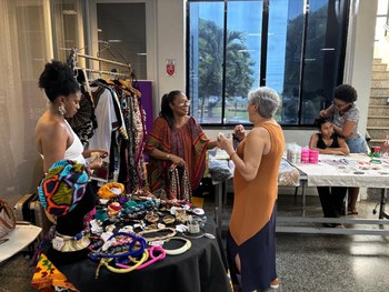 A imagem mostra uma mesa redonda coberta com toalha branca, onde estão expostos diversos itens a...