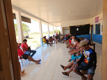 A imagem mostra uma sala organizada como biblioteca, com estantes verdes cheias de livros ao fun...