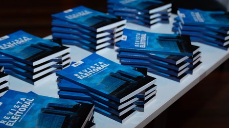 A foto mostra uma mesa comprida, coberta com toalha branca, onde vários homens de terno estão se...