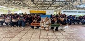 A imagem mostra um grupo grande de pessoas reunidas em um espaço coberto, semelhante a uma área ...