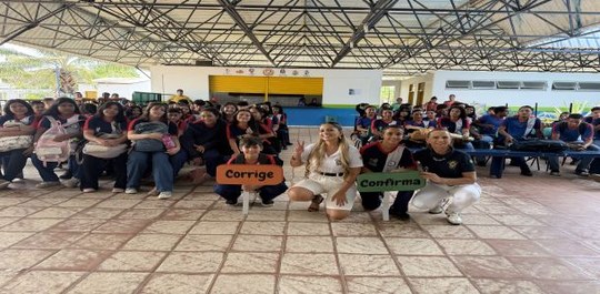 A imagem mostra um grupo grande de pessoas reunidas em um espaço coberto, semelhante a uma área ...