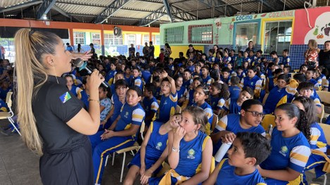 A imagem mostra uma pessoa posicionada diante de uma urna eletrônica. A mão dessa pessoa está ap...