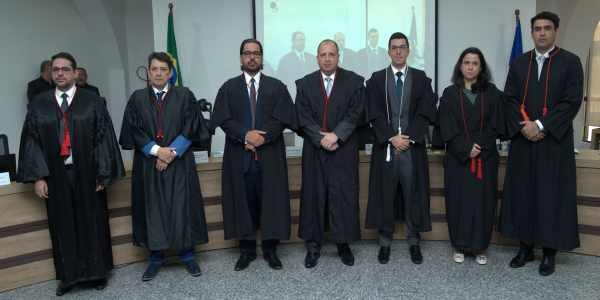 Posse dos novos juizes eleitorais Imagem mostra sete pessoas adultas em pé, lado a lado, usando vestes formais pretas típicas do J...