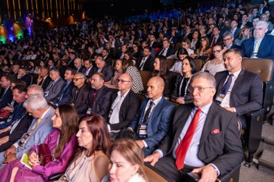 A imagem mostra um homem de terno cinza claro sorrindo e segurando um troféu azul do Prêmio CNJ ...
