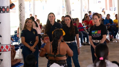 Em uma maloca com cobertura de palha, dezenas de jovens indígenas participam de uma atividade ed...