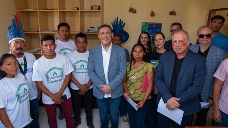 Em uma maloca com cobertura de palha, dezenas de jovens indígenas participam de uma atividade ed...