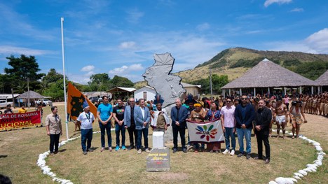 Em uma maloca com cobertura de palha, dezenas de jovens indígenas participam de uma atividade ed...