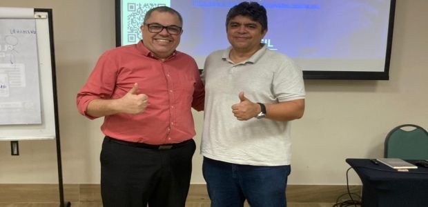 #pracegover #pratodomundover #acessibilidade - Na foto, em uma sala de paredes brancas, 02 homen...