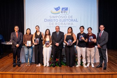 Mesa com várias pilhas de cartilhas organizadas, com capa em tom marrom contendo o texto “Meu Pr...