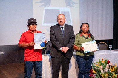 Mesa com várias pilhas de cartilhas organizadas, com capa em tom marrom contendo o texto “Meu Pr...