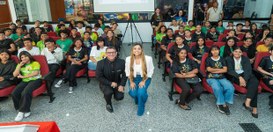 Auditório com várias fileiras de cadeiras ocupadas por um grande grupo de estudantes sentados e ...