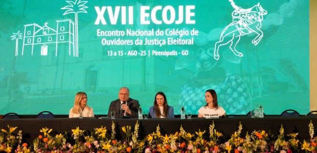 TRE-RR - Apresentação da 1ª Ouvidoria Eleitoral Indígena Quatro pessoas sentadas, 3 mulheres e 1 homem, com uma bancada preta a frente ; no fundo um p...
