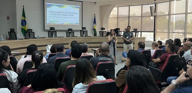 Foto de um auditório durante um treinamento para as Eleições Gerais 2026. Diversas pessoas estão...