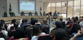 Foto de um auditório durante um treinamento para as Eleições Gerais 2026. Diversas pessoas estão...