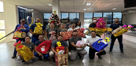 Grupo de cerca de 15 pessoas posa em um ambiente interno, provavelmente um local de trabalho. El...