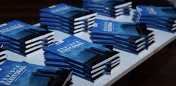Uma mesa branca está cheia de pilhas de livros de capa azul. Na capa, lê-se “Revista Eleitoral” ...