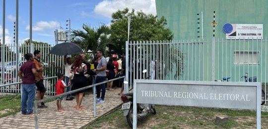 Foto externa de um prédio público com fachada verde, identificado por placas como Tribunal Regio...