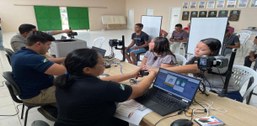 Pessoas participam de atendimento para emissão de título de eleitor. Em uma sala, servidores uti...