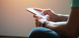 Close de uma pessoa segurando um celular com as duas mãos e interagindo com a tela sensível ao t...