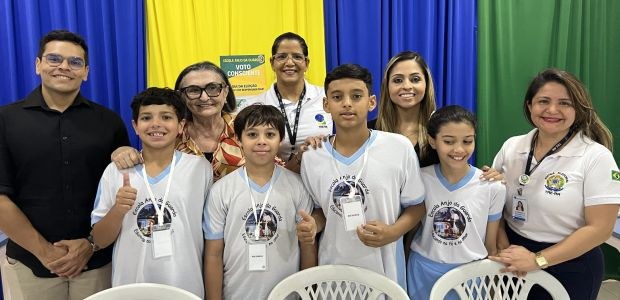 A imagem mostra um grupo de pessoas posando juntas em frente a um fundo com cortinas nas cores a...