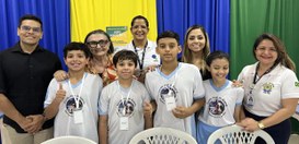 A imagem mostra um grupo de pessoas posando juntas em frente a um fundo com cortinas nas cores a...