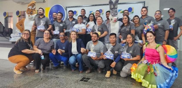 TRE-RR promove campanha Adoçando Vidas – Páscoa Solidária A imagem mostra um grande grupo de pessoas reunidas em um ambiente interno, que parece ser um sa...
