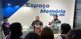 Ambiente interno de exposição com paredes nas cores branca e azul, com o texto “Espaço Memória T...