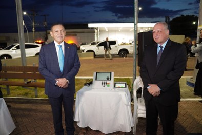 Em uma atividade pública realizada à noite, uma pessoa utiliza uma urna eletrônica posicionada s...