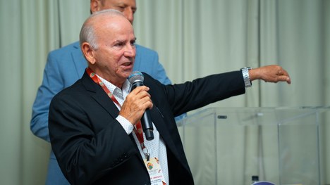 A imagem mostra um grande grupo de pessoas reunidas para uma foto oficial em um evento. São cerc...