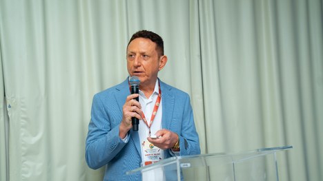 A imagem mostra um grande grupo de pessoas reunidas para uma foto oficial em um evento. São cerc...