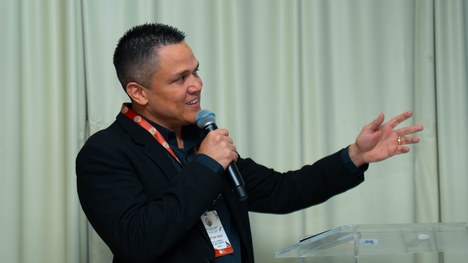 A imagem mostra um grande grupo de pessoas reunidas para uma foto oficial em um evento. São cerc...