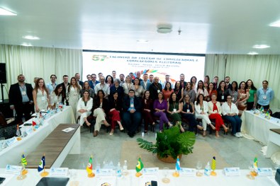 A imagem mostra um grande grupo de pessoas reunidas para uma foto oficial em um evento. São cerc...