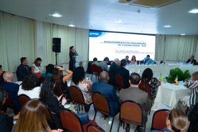 A imagem mostra um grande grupo de pessoas reunidas para uma foto oficial em um evento. São cerc...
