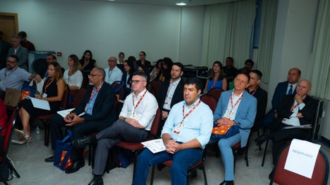A imagem mostra um grande grupo de pessoas reunidas para uma foto oficial em um evento. São cerc...