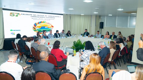 A imagem mostra um grande grupo de pessoas reunidas para uma foto oficial em um evento. São cerc...