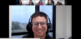 Homem sorridente usando fones de ouvido e óculos participa de uma videoconferência. Na parte sup...