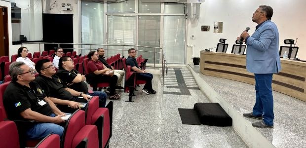 TRE-RR- Capacitação oficiais de justiça Homem em pé fala ao microfone em um auditório para um pequeno grupo de pessoas sentadas em cadei...