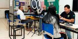 Foto mostra atendimento eleitoral em uma sala de escola. Servidores do TRE-RR estão sentados em ...